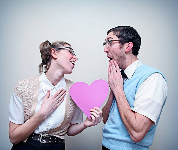 милый зануда guy and girl in love, держа сердце - valentines day love nerd couple стоковые фото и изображения