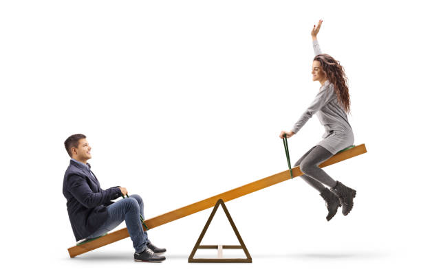 Young couple on a seesaw Young couple on a seesaw isolated on white background adult seesaw stock pictures, royalty-free photos & images