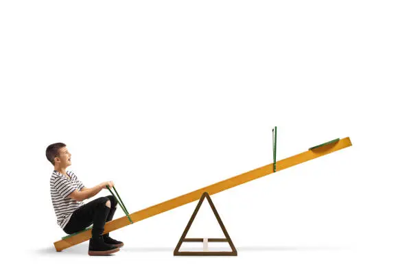 Full length shot of a smiling boy sitting alone on a seesaw isolated on white background
