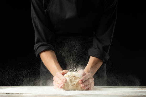 istock Bakery. Man preparing the bread, Easter cake, Easter bread or cross buns on a wooden table in the bakery close up. Cook preparing bread dough. 1081952704