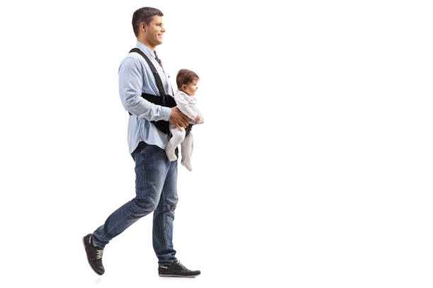 Full length shot of a father walking with a baby in carrier  isolated on white background
