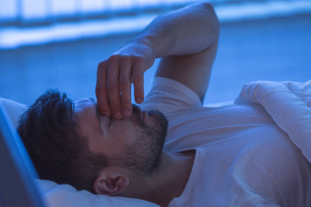 the man with a headache sleeping on the bed. night time - insomnia imagens e fotografias de stock