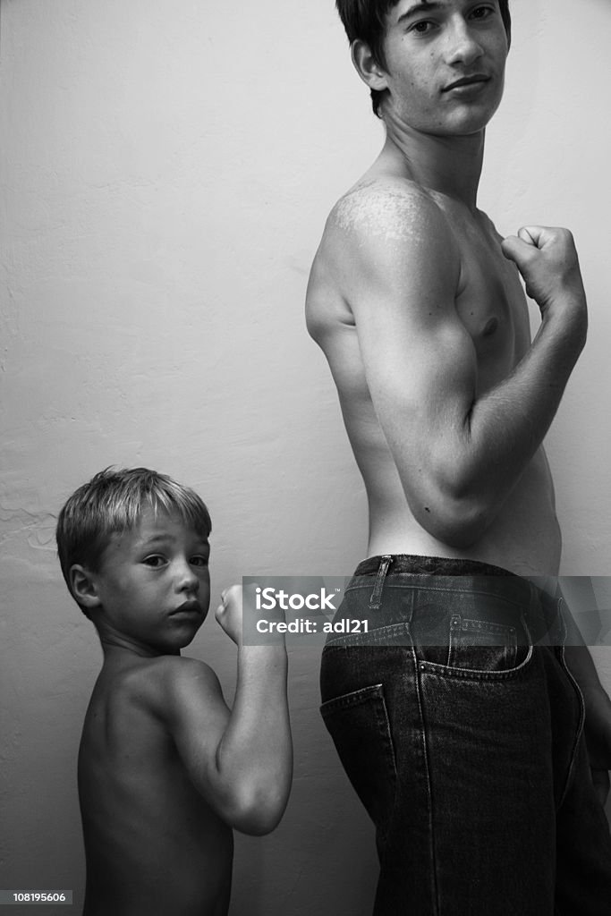 Portret Mały chłopiec i starszy brat Napinać grupy mięśni - Zbiór zdjęć royalty-free (Nadzieja)