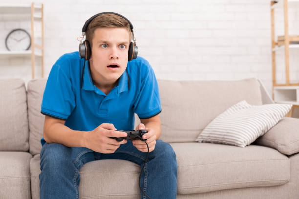 Teen guy playing video games with joystick