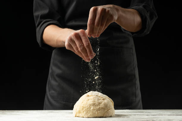 Bakery. Man preparing the bread, Easter cake, Easter bread or cross buns on a wooden table in the bakery close up. Cook preparing bread dough.
