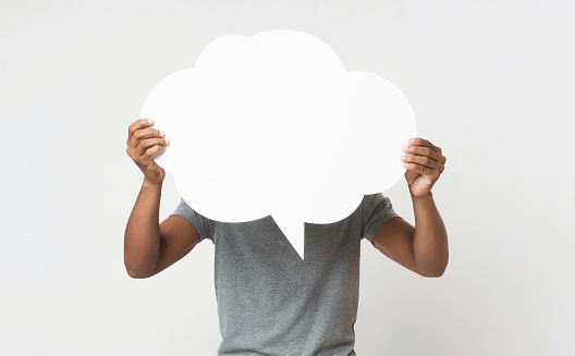 Black guy covering his face with blank speech bubble, copy space