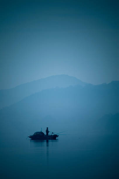 Man standing  and using rod and hook on boat to  fishing