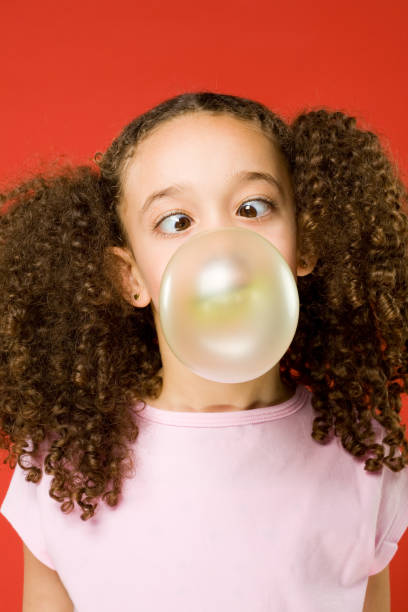 Color image of a little girl trying to blow a bubble with her bubble gum.