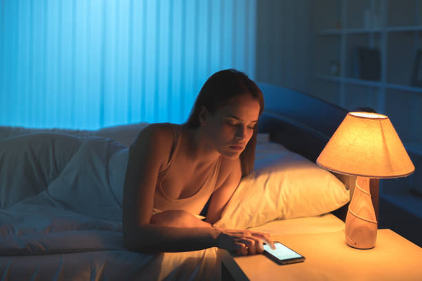 le téléphone de la femme attirante dans le lit. temps de nuit - telephone window mobile phone addiction photos et images de collection