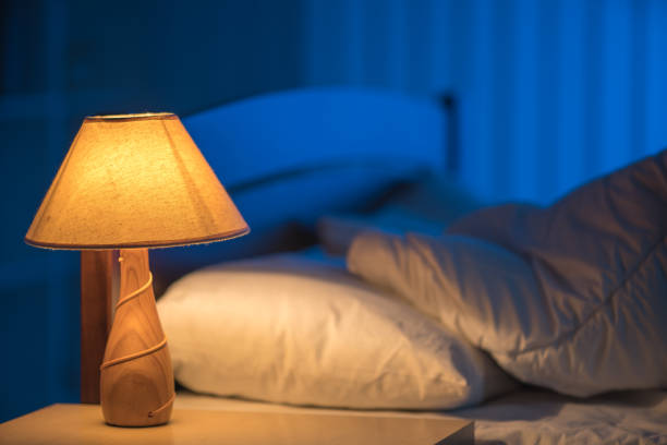ベッドの背景に対するランプ。夜の時間 - 寝室 ストックフォトと画像