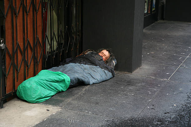 Homeless in sleeping-bag on the street stock photo