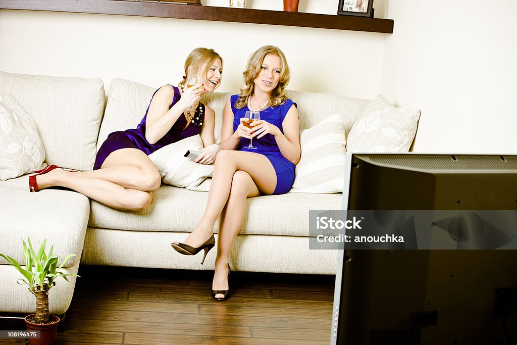 Duas mulheres bebendo vinho, conversando e assistir televisão - Foto de stock de Amizade royalty-free