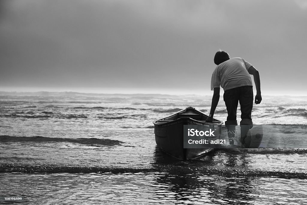 Homme tirant un Canoë en eau, noir et blanc - Photo de Se courber en avant libre de droits