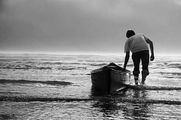 Uomo tirando In acqua Canoa, bianco e nero - foto stock