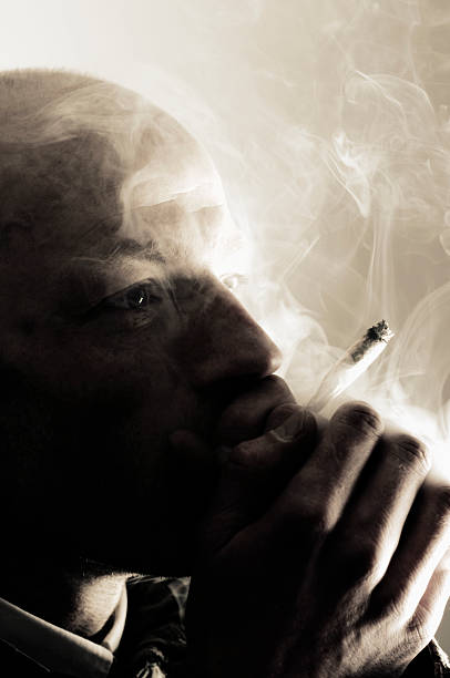 istock Man Smoking Marijuana Cigarette in Cloud of Smoke 108196510