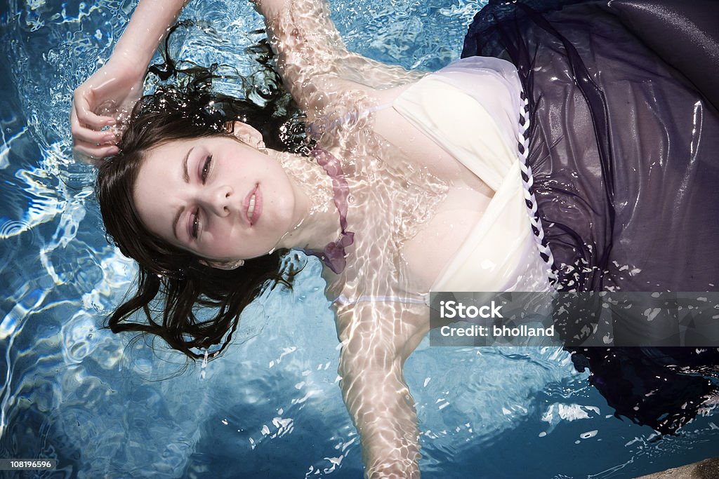 Giovane donna che indossa abito e galleggiante in acqua - Foto stock royalty-free di Acqua