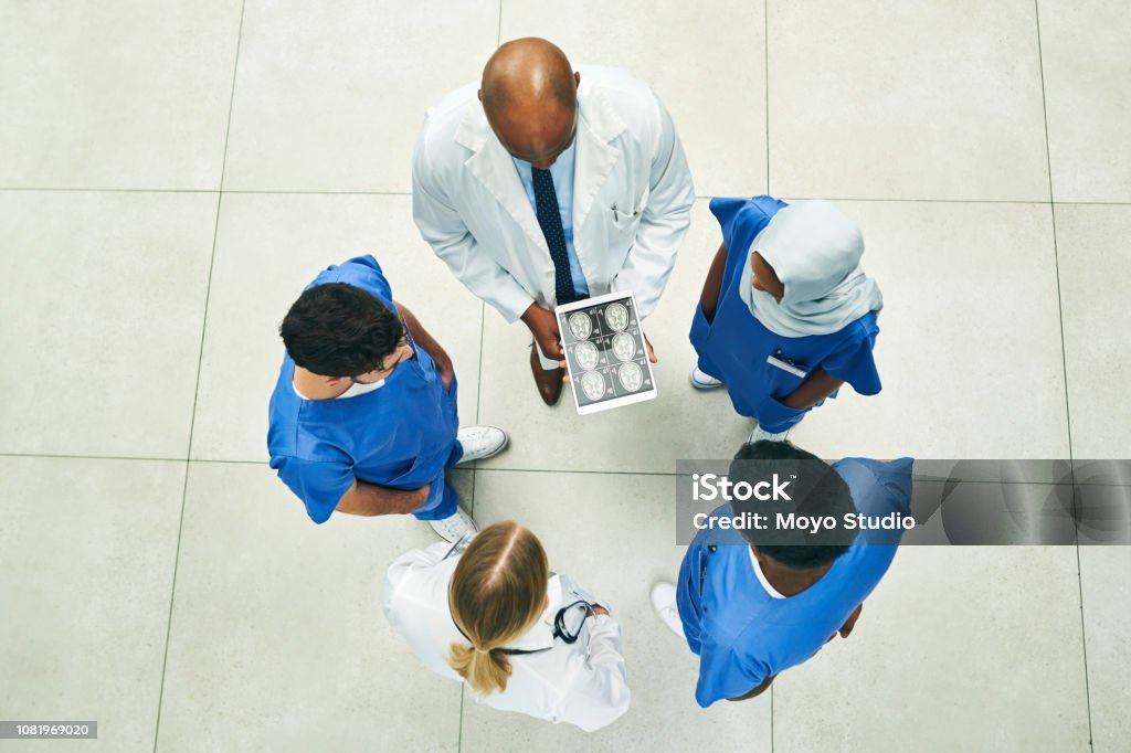 Saving lives is up to the team High angle shot of a team of doctors using a digital tablet to view scans in a hospital Directly Above Stock Photo Saving lives is up to the team High angle shot of a team of doctors using a digital tablet to view scans in a hospital Directly Above Stock Photo