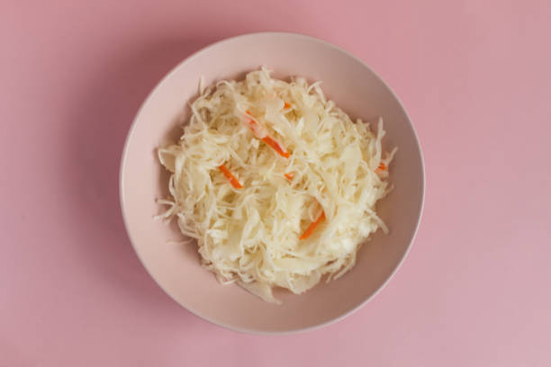 パステル ピンク色背景平面図上にボウルにキャベツの酢漬け。 - sauerkraut salad coleslaw cabbage ストックフォトと画像
