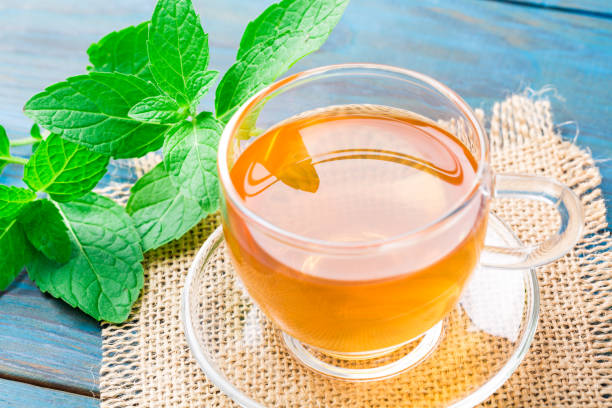 istock Cup of mint tea on blue wood textured background 1081969684