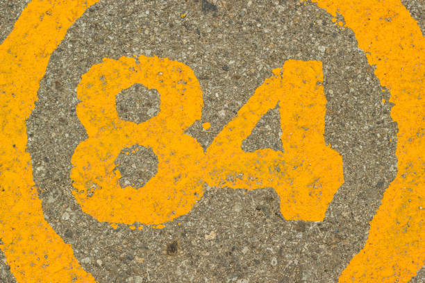 istock The number 84 embedded in asphalt concrete. 1081970736
