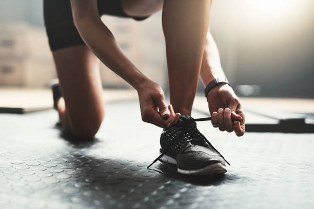 You have to wear the correct shoes when exercising Cropped shot of an unrecognizable woman tying her shoelaces in the gym lace fastener photos stock pictures, royalty-free photos & images