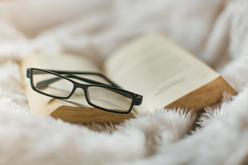 an old book on blankie blanket with horn-rimmed eye glasses in a peaceful scene