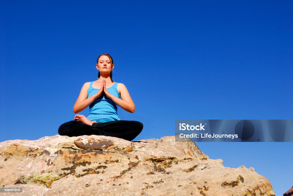 Mujer en posición de loto con gran cielo azul de fondo - Foto de stock de Actividades y técnicas de relajación libre de derechos