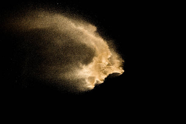 Golden sand explosion isolated on black background. Abstract sand cloud.