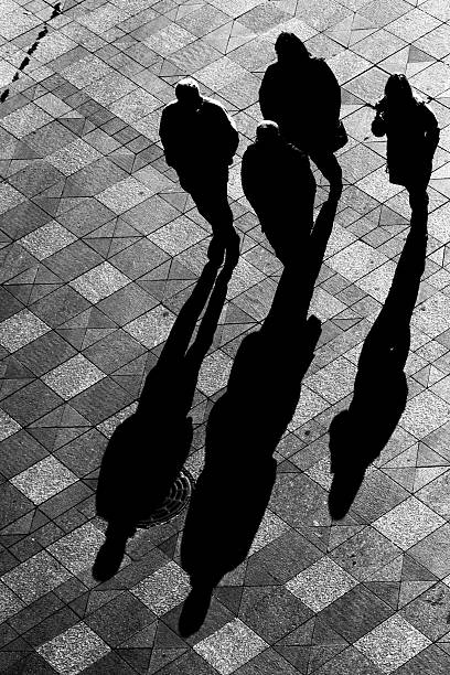 istock Silhouette of Group with Shadows Walking on Tiled Sidewalk 108198113