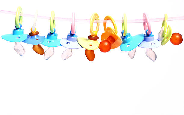 Many baby pacifiers hanging from a string stock photo