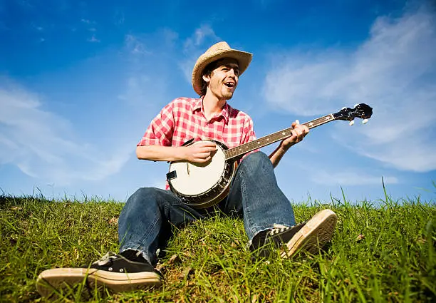 Photo of Country boy plays the banjo in a rural summer meadow