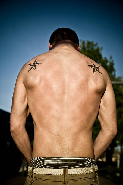 Man Showing Off Muscular Back with Tattoos  shoulder tattoo designs for men stock pictures, royalty-free photos & images