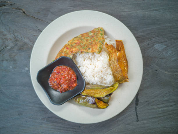 istock Selective focus of Malaysian favourite dish for lunch or dinner. White rice, shrimp paste, fried fish, omelette and fried eggplant on the top of wooden table. 1081988782