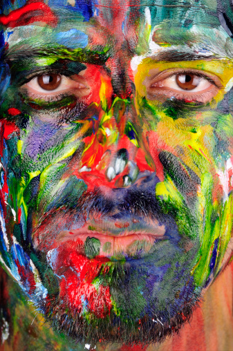 Close up shot of a man who has a painted face. 