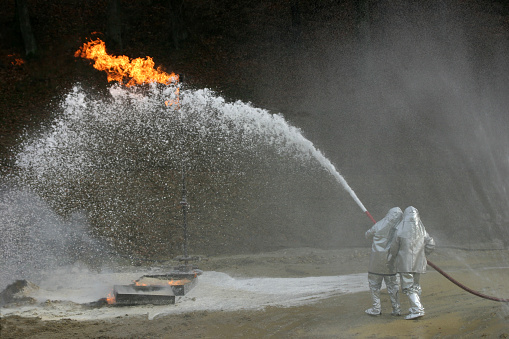 Firefighters crew wearing green coveralls and equipped with a tank of compressed air and a mask for Chemical Accident and Toxic Risk