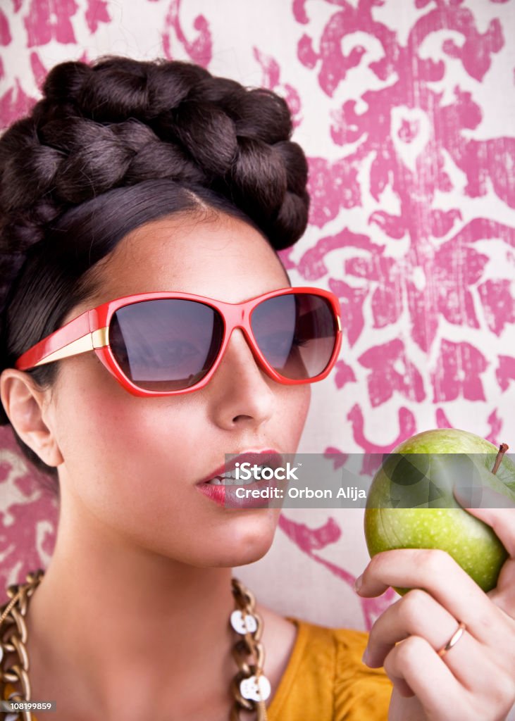 レトロなサングラスを着ている若い女性のリンゴを食べる - 1人のロイヤリティフリーストックフォト