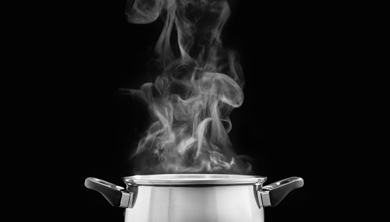 steam over cooking pot in kitchen on dark background