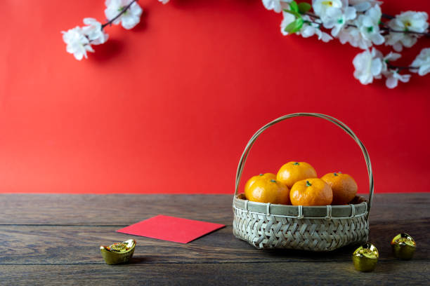 acessórios em fundo de conceito do ano novo lunar chinês de ano novo e férias. laranja na cesta de madeira com dinheiro de bolso vermelho e flor no moderno cenário rústico marrom e vermelho no estúdio de mesa de escritório em casa. - flower china frame chinese culture - fotografias e filmes do acervo