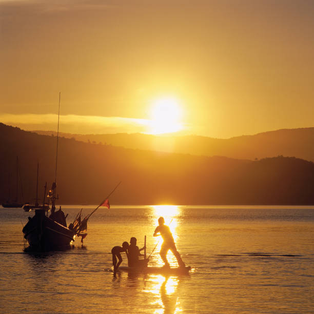 Three boys play on a makeshift boat as the sun sets behind. Samui Island (Koh Samui), Thailand. \n\nMore similar images below.\n\n[url=file_closeup.php?id=14923160][img]file_thumbview_approve.php?size=1&id=14923160[/img][/url] [url=file_closeup.php?id=14690973][img]file_thumbview_approve.php?size=1&id=14690973[/img][/url] [url=file_closeup.php?id=14690961][img]file_thumbview_approve.php?size=1&id=14690961[/img][/url] [url=file_closeup.php?id=13530645][img]file_thumbview_approve.php?size=1&id=13530645[/img][/url] [url=file_closeup.php?id=12978431][img]file_thumbview_approve.php?size=1&id=12978431[/img][/url] [url=file_closeup.php?id=9258775][img]file_thumbview_approve.php?size=1&id=9258775[/img][/url] [url=file_closeup.php?id=9088657][img]file_thumbview_approve.php?size=1&id=9088657[/img][/url] [url=file_closeup.php?id=23674262][img]file_thumbview_approve.php?size=1&id=23674262[/img][/url] [url=file_closeup.php?id=15791390][img]file_thumbview_approve.php?size=1&id=15791390[/img][/url] [url=file_closeup.php?id=12928979][img]file_thumbview_approve.php?size=1&id=12928979[/img][/url]\n\nCLICK ON THE BOXES BELOW FOR MORE RELATED IMAGES FROM MY PORTFOLIO.\n\n[url=http://www.istockphoto.com/search/lightbox/8535141#b22015c][img]http://www.markstandenpublishing.com/_banners/thailand.jpg[/img][/url]\n\n[url=http://www.istockphoto.com/search/lightbox/6350712#17ccb8c8][img]http://www.markstandenpublishing.com/_banners/boats.jpg[/img][/url]\n\n[url=http://www.istockphoto.com/search/lightbox/6350702#194c21fd][img]http://www.markstandenpublishing.com/_banners/serenity.jpg[/img][/url]