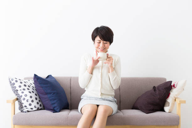 istock A woman sitting on a couch and enjoying a drink 1082006368