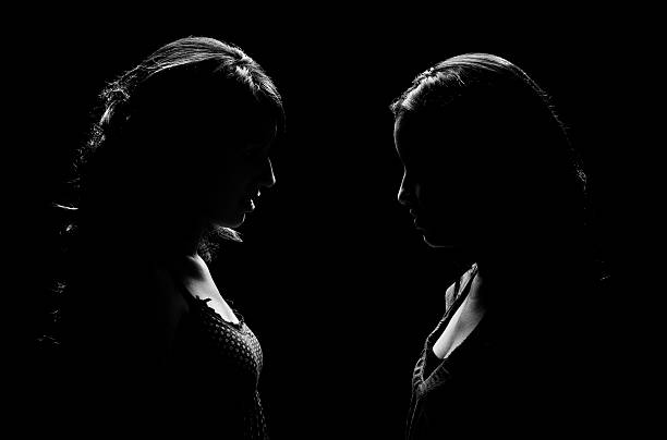 Low Key Lit Portrait of Two Woman Facing Each Other  confrontation stock pictures, royalty-free photos & images