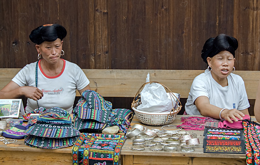 Longji, China - July 15, 2010: Red Yao women selling products to tourists. Red Yao women of Huangluo are known for the âworldâs longest hair villageâ. Longsheng Huangluo Yao Village. Guilin, Guangxi, China.