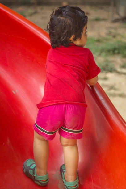 Small Indian Kid trying to climbs on Slides in Public Park.