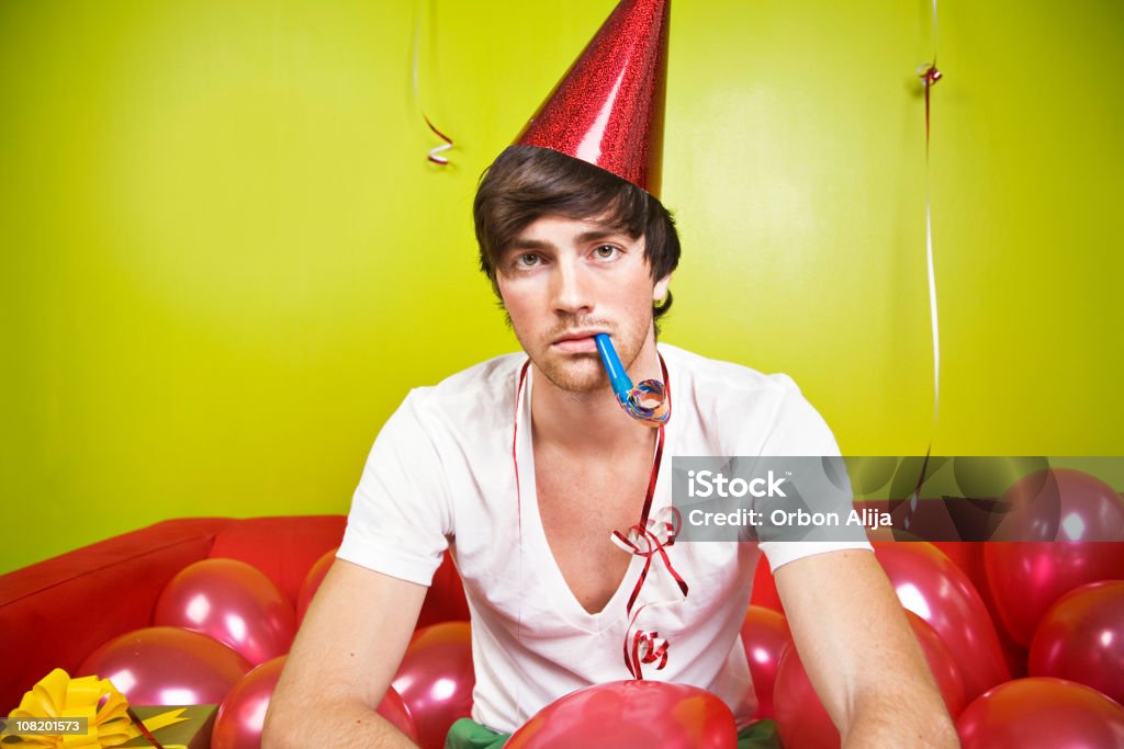 Grave joven usando gorro de fiesta con globos, Soplando bocina - Foto de stock de Fiesta libre de derechos