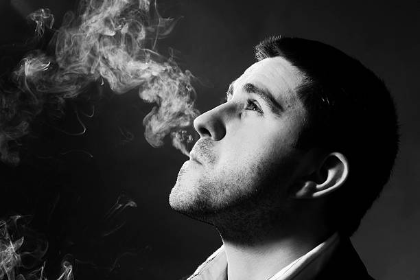 istock Portrait of man blowing cigarette smoke, black and white 108201848