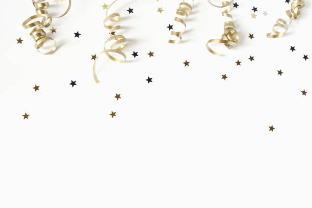 Happy New Year or birthday festive composition. Golden confetti and glittering stars on white table background. Celebration, party concept. Flat lay, top view. Empty copy space. stock photo