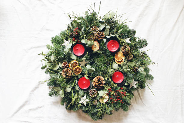 corona dell'avvento di natale isolata su sfondo bianco. decorato da rami di abeti sempreverdi, foglie di eucalipto, stelle di legno, pigne, bacche e candele rosse. lay piatto, vista dall'alto. - christmas branch pine tree evergreen tree foto e immagini stock