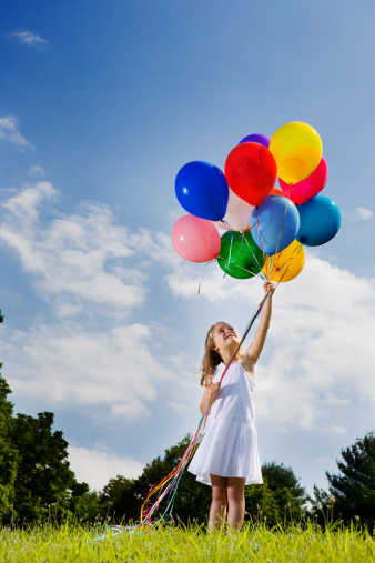 Cheerful beauty woman holding balloons relax sitting under big tree in green park with happiness. Woman Hands holding vibrant air balloons play on birthday party happy time summer on sunshine outdoor