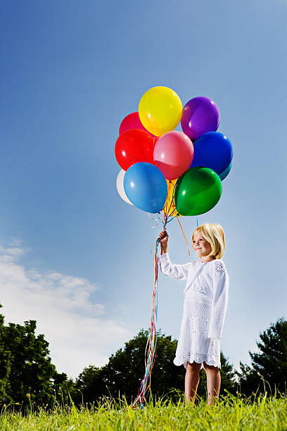 istock Little girl with multicolored balloons stands smiling 108201935