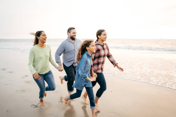 istock Two parents and two kids running on the beach 1082024016